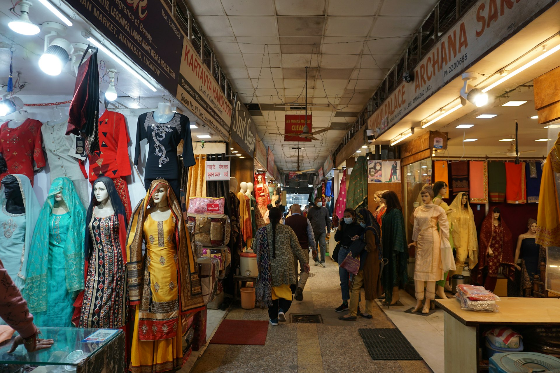 Aisle of an Indian clothing market lined with mannequins in kurtas and sarees