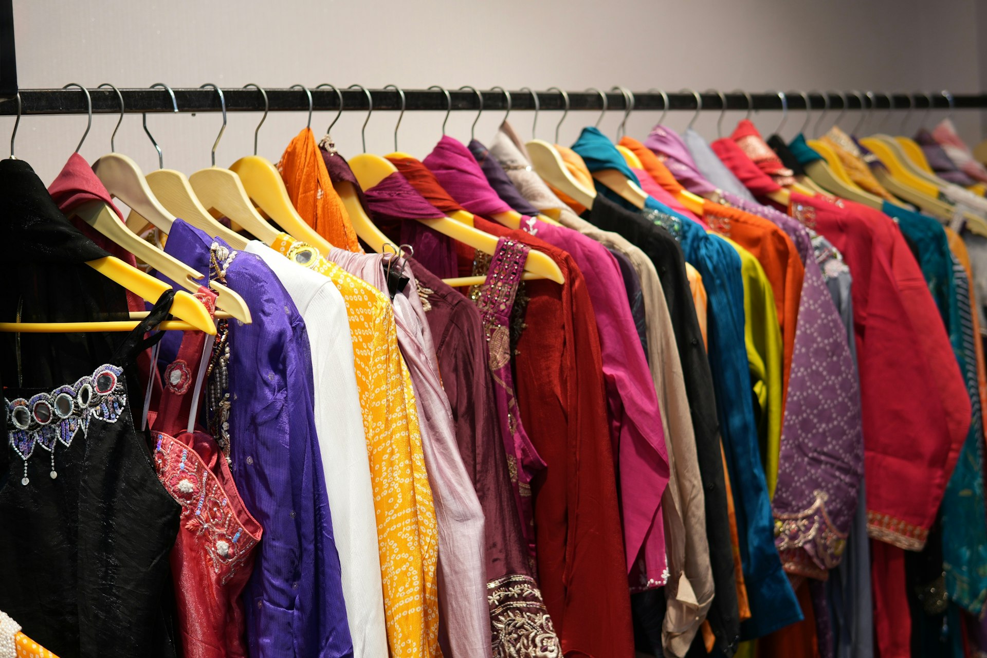Colourful Indian ethnic wear on wooden hangers at a garment shop